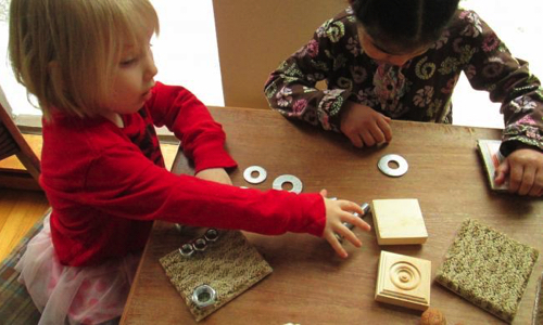 Two kids playing with a objects on a table