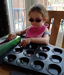 IEllie playing with buttons in a muffin tin