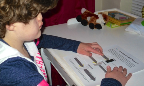 Madilyn touches the tactile worksheet her mother created for her