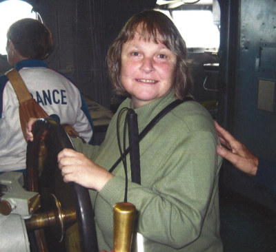 Marianne at the steering wheel of a large boat.