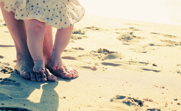 Mom and baby with their feet in the sand