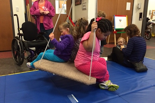 Little kids on a platform swing.