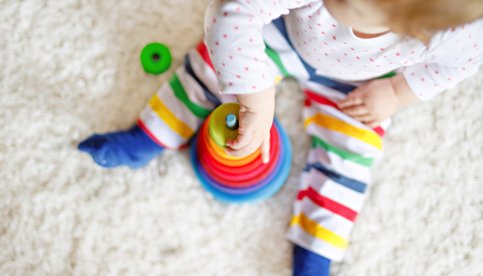 baby girl sitting on the floor with a stacking toy