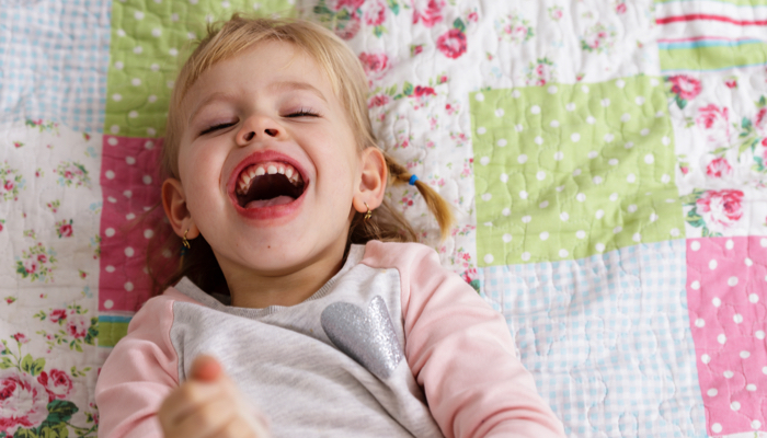 little girl laughing on a bed