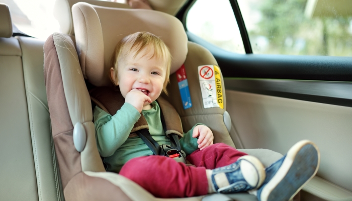 Adorable toddler boy sitting safely in a car seat.