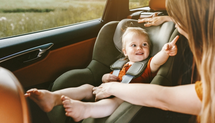 Child in car baby sitting in safety seat mother fasten belt family lifestyle travel vacation with kid.