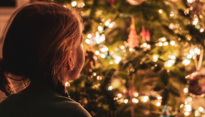 a little girl looking at a Christmas tree