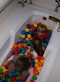 Kids in a bathtub full of plastic balls