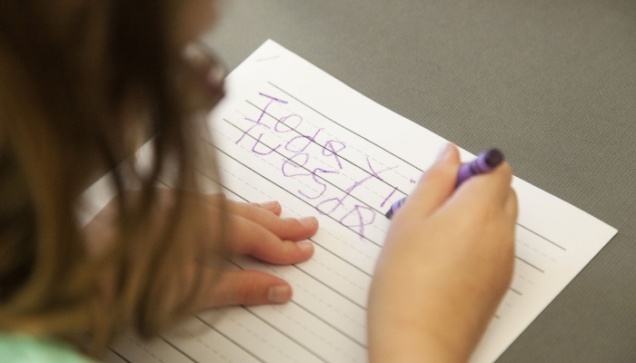 girl with low vision writing with a crayon