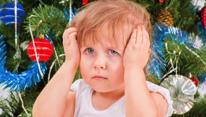 little girl frowning in front of christmas tree