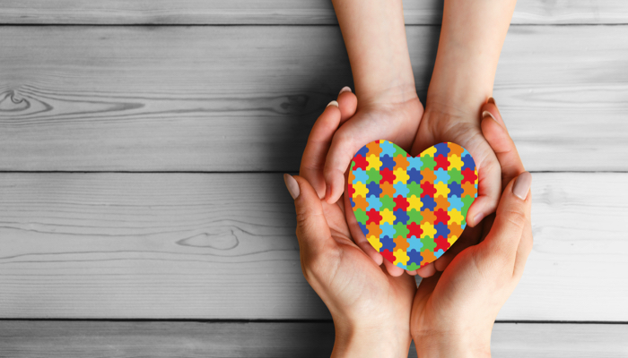 hands holding a colorful heart shaped puzzle