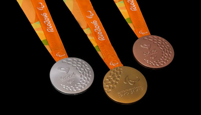 3 Paralympic Medals with orange ribbon on black background