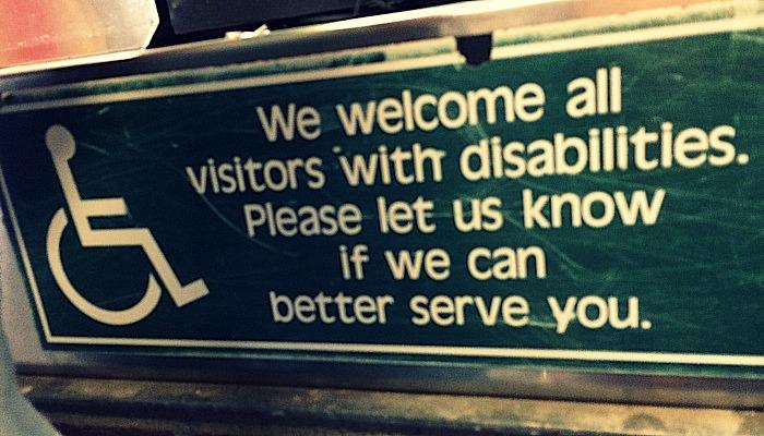 sign reading We welcome all visitors with disabilities. Please let us know if we can better serve you.