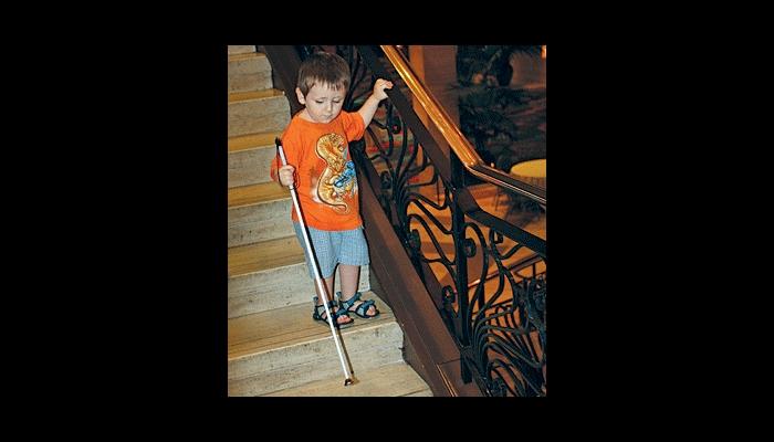 Boy walking on stairs with his cane