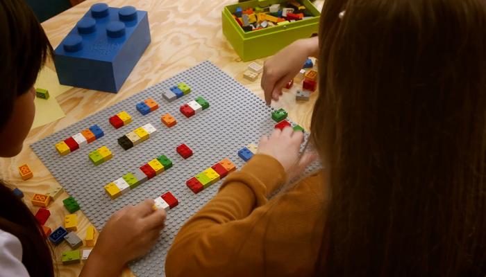 Children playing with colored braille bricks on a table