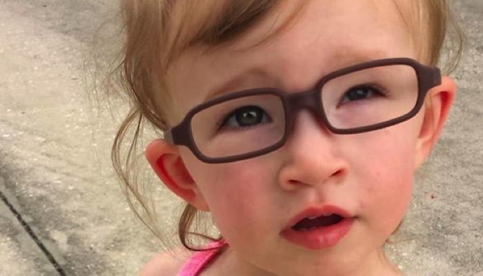 little girl wearing purple glasses