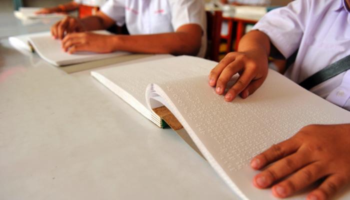 students reading braille in a classroom