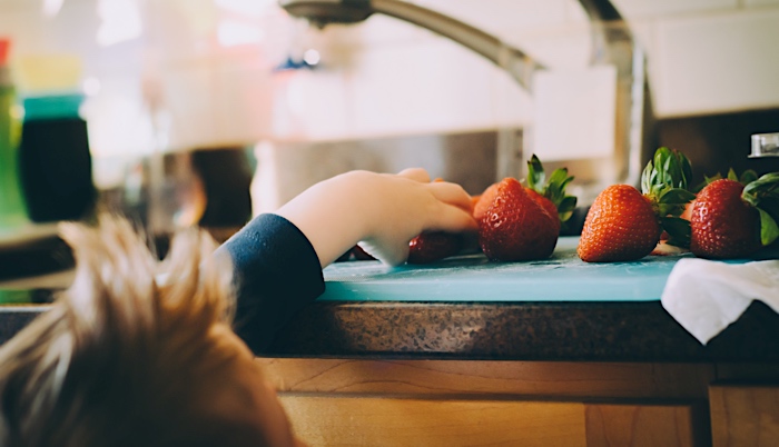 boy reaching for a strawberry