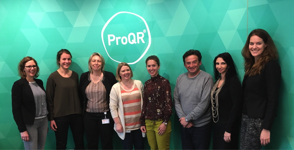 photo of 7 ProQR LCA team members (1 man, 7 women) and Laura Steinbusch in front of a green wall with a white ProQR logo.