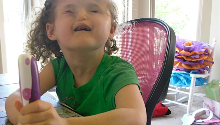 Madilyn is happily reading braille and using her LeapFrog reader