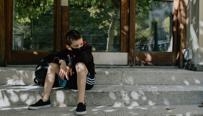 boy wearing a black mask outside school