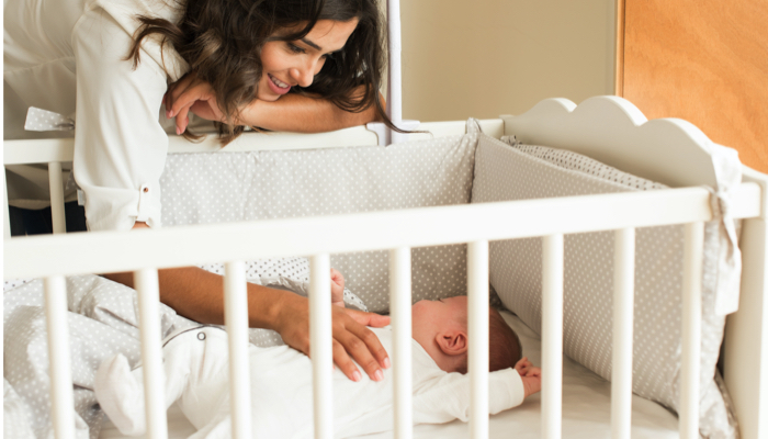 mom touching baby in her crib