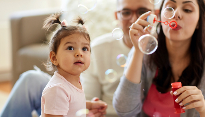 mom blowing bubbles for toddler