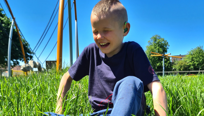 Cameron sitting in the grass and smiling