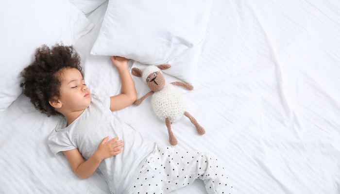 Little girl napping with doll.