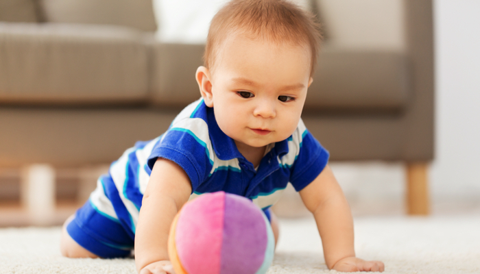 baby boy crawling toward a plush ball