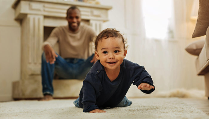 baby crawling while proud dad watches