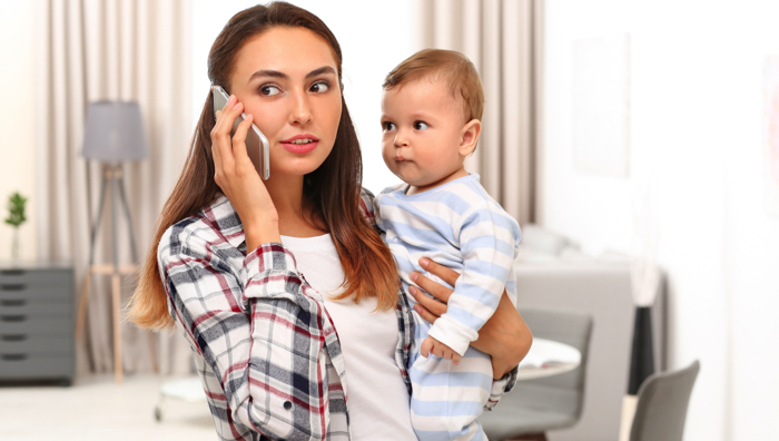 mother holding baby and talking on the phone