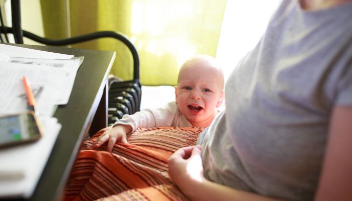 Crying baby crawling on moms' lap.