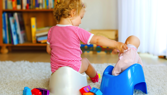 Girl potty training with her doll.