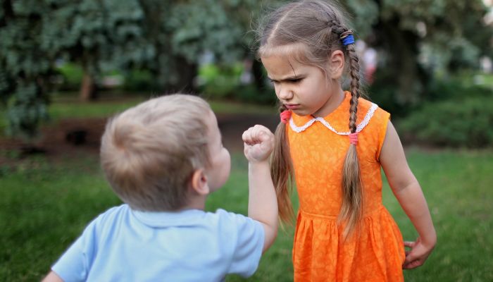 Toddler shaking fist at sister.