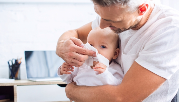 Daddy cleaning up baby's nose.