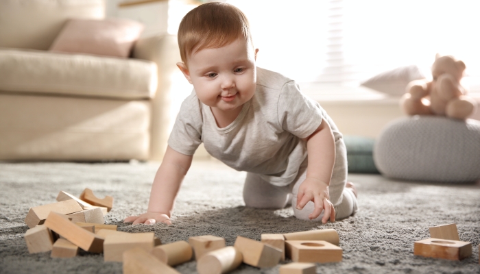 Cute baby playing with wooden blocks at home.