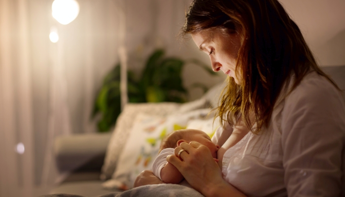 Young beautiful mother, breastfeeding her newborn.