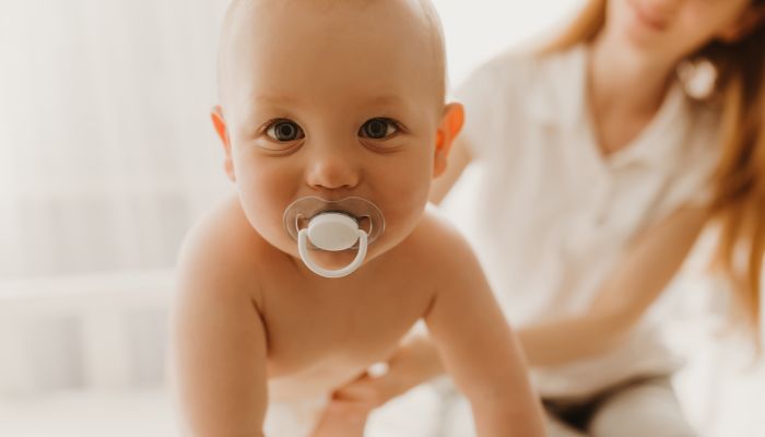 Crawling baby with pacifier.