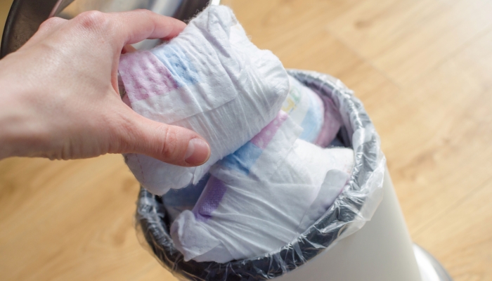 Disposing diaper in trash bin.