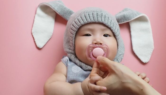 Mom holding pacifier in baby's mouth.