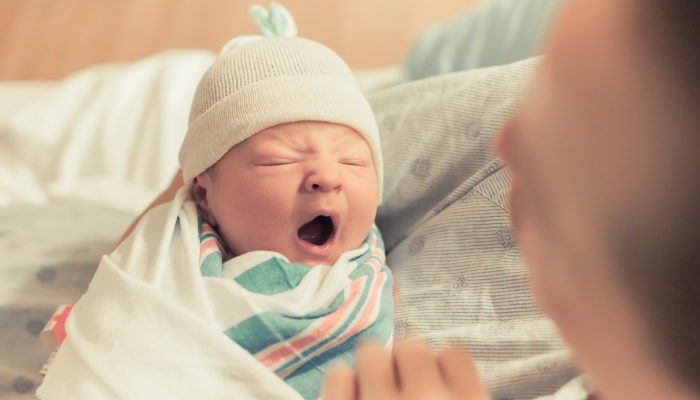 Mother holding her baby in a receiving blanket.