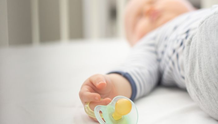 Sleeping baby holding pacifier.