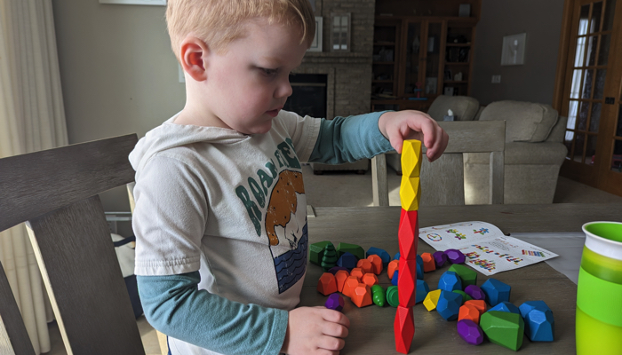 Young boy playing with wooden stacking rocks.