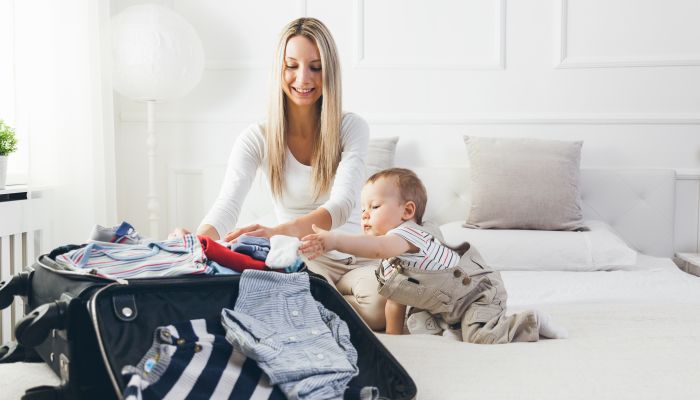 Baby and mom packing suitcase.