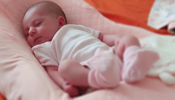 A newborn baby sleeps in a special orthopedic mattress.