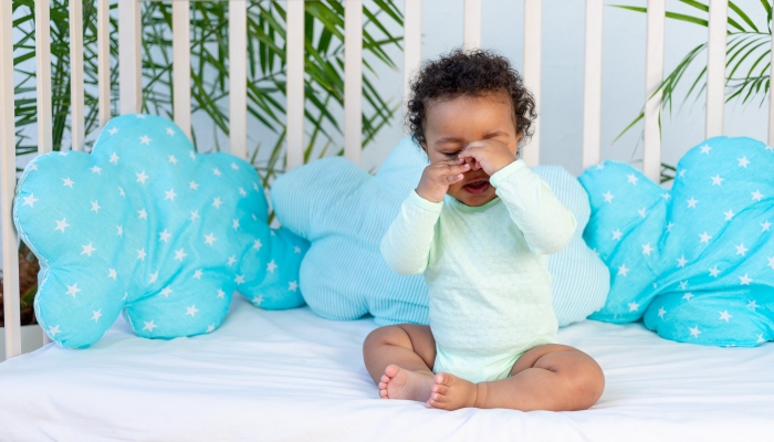 African baby rubs his eyes before going to bed.