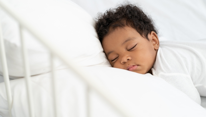 Baby sleeping on a white mattress.