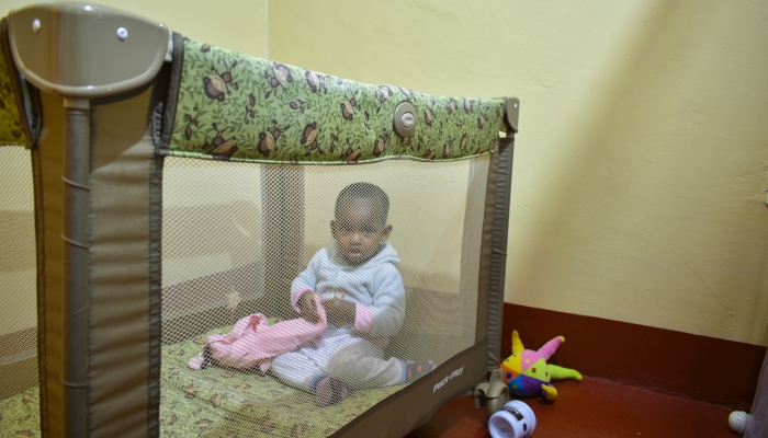 Child plays in a pack 'n play baby bassinet.