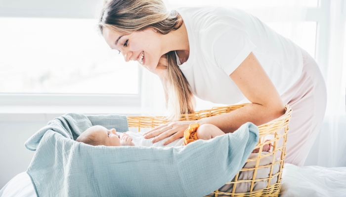 Mother comforting newborn daughter in bassinet.